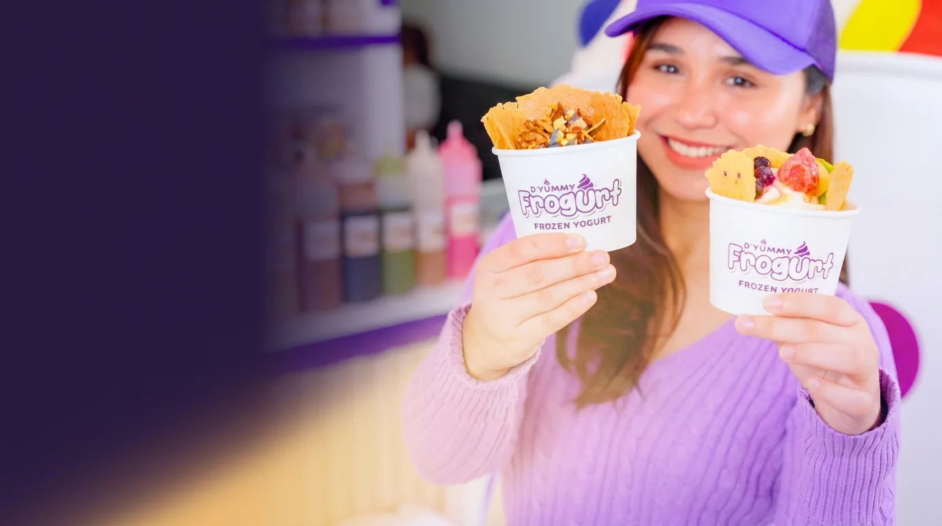 D'Yummy Frogurt crew member presenting two frozen yogurt cups in a cinematic franchise campaign